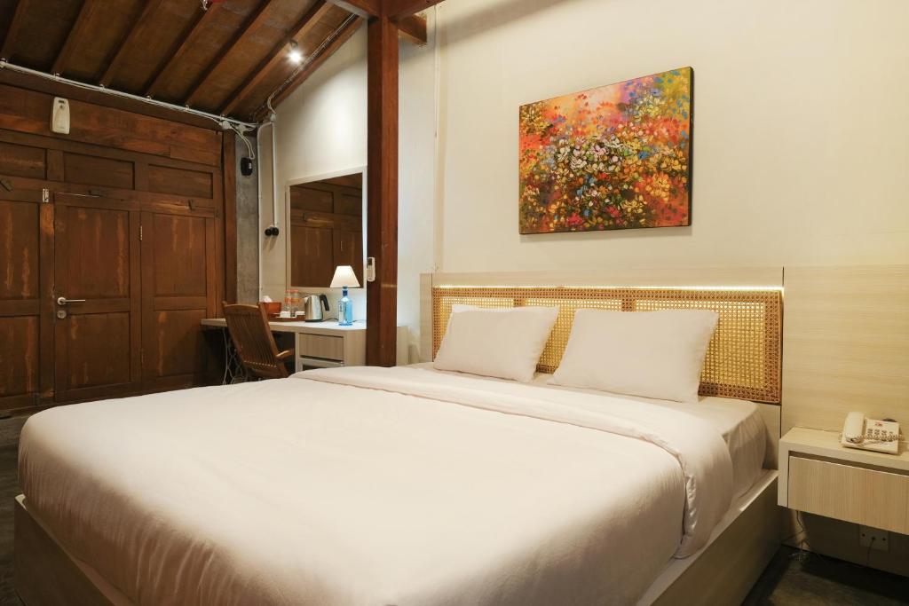 日惹Kampung Lawasan Heritage Cottage的卧室配有一张床,墙上挂有绘画作品
