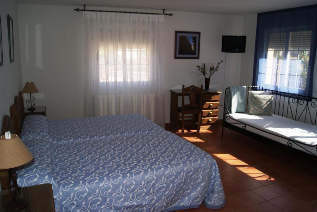NohalesHabitaciones Casa Rural El Sauce的一间卧室配有一张床、一张沙发和一个窗口