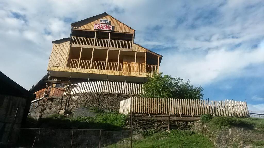 OmaloGuest House Tsasne的山顶上带有栅栏的木结构建筑