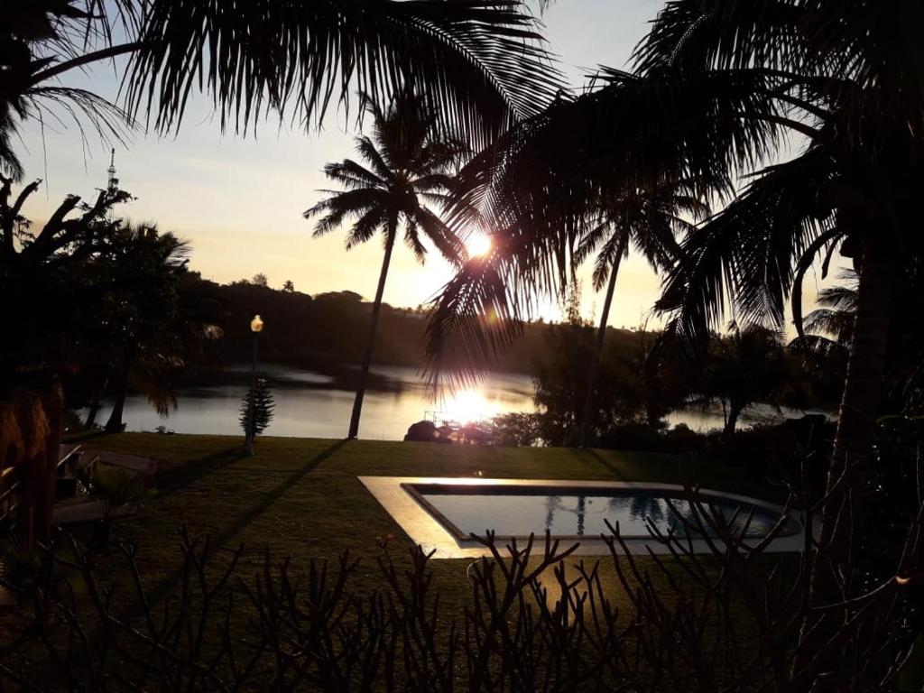 普拉伊拉多比莱尼Bilene Dream House 1的棕榈树和水体的池塘上的日落