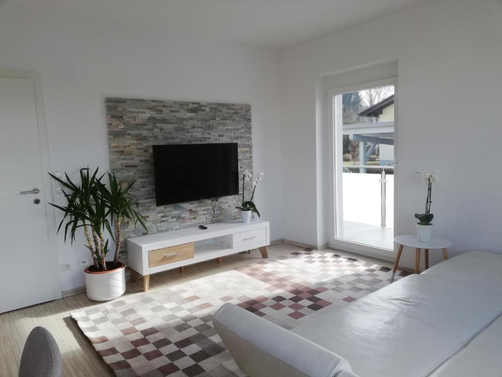 格拉特科恩Gemütliches 3 Zimmer Apartment nahe Graz的一间白色的客厅,在砖墙上配有电视