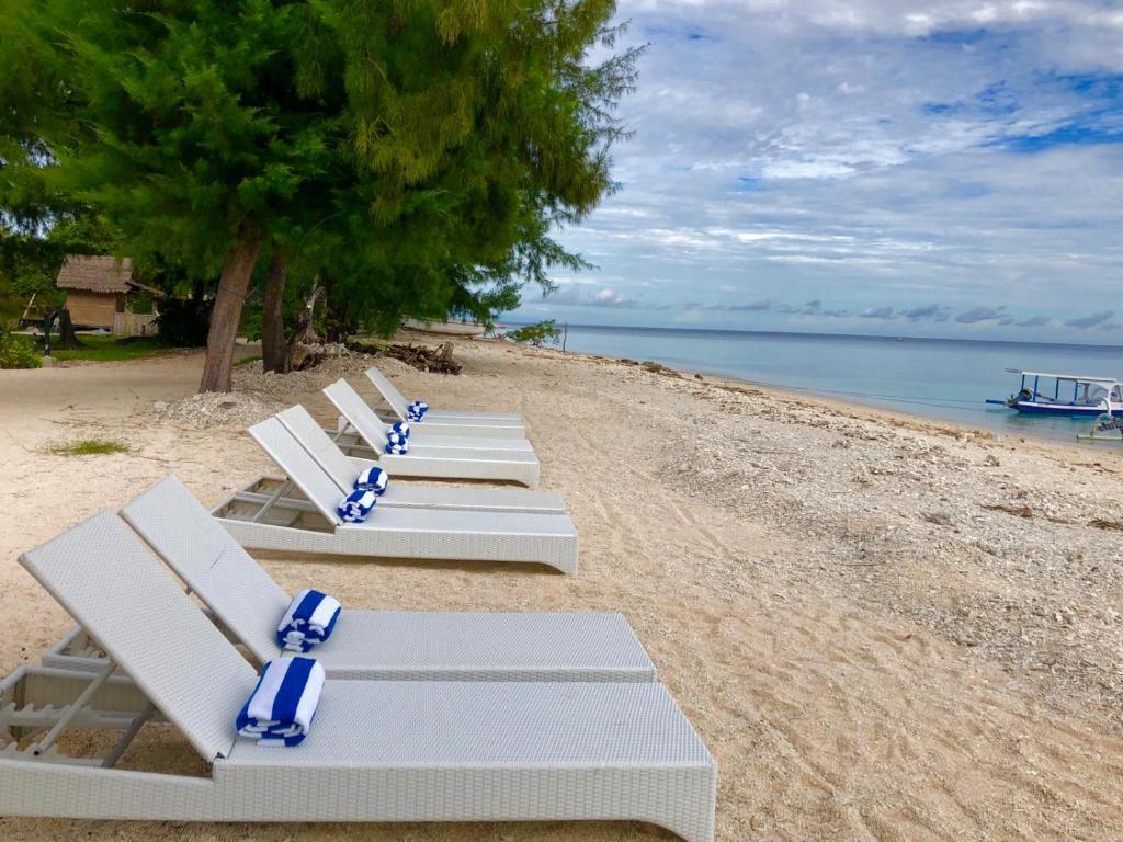吉利美诺Villa Samalas Resort and Restaurant的海滩上一排白色躺椅
