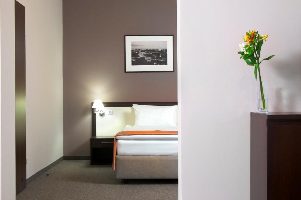 利沃夫利沃夫华美达酒店的配有一张床和花瓶的酒店客房