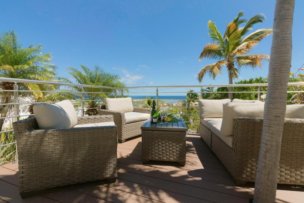 圣马丁岛VILLA SAPHIR的一个带柳条椅和棕榈树的庭院以及大海
