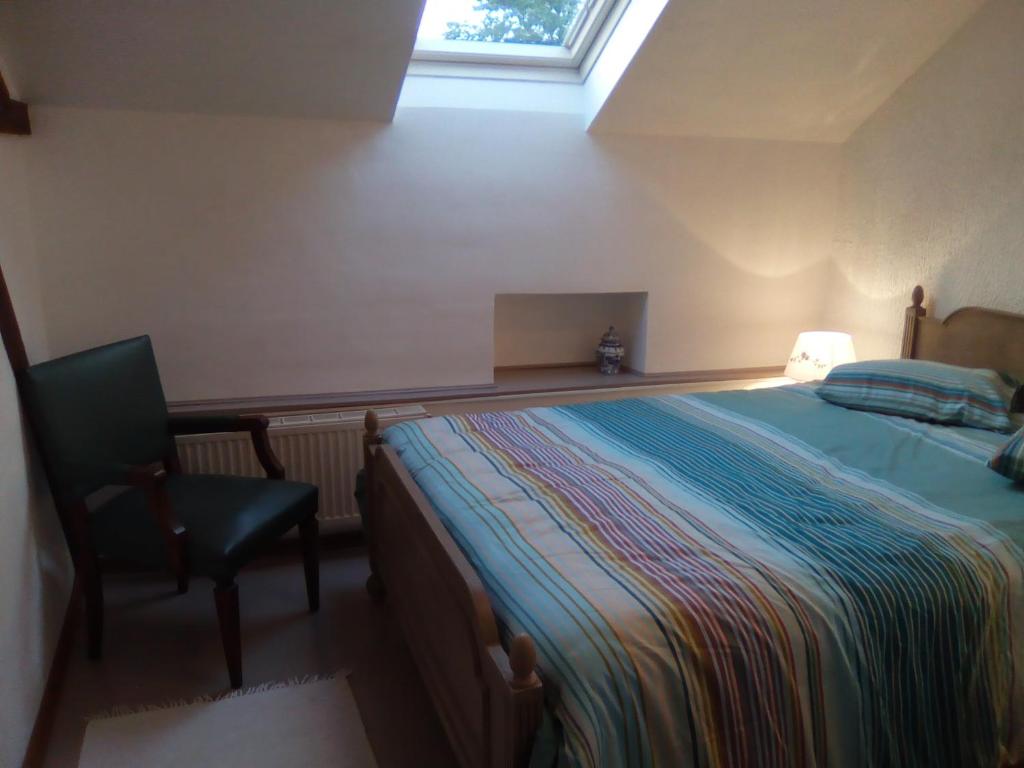 萨乌丁Le Clos Fleuri的卧室配有床、椅子和窗户。