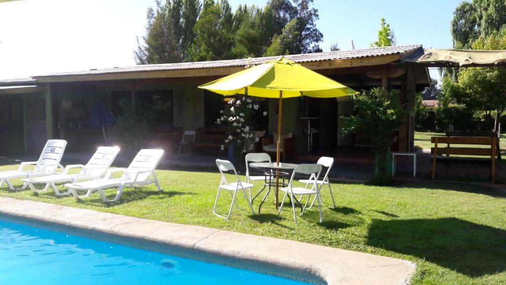 PaineCabaña Campestre de 1 Ambiente En Paine的游泳池旁配有遮阳伞的桌椅