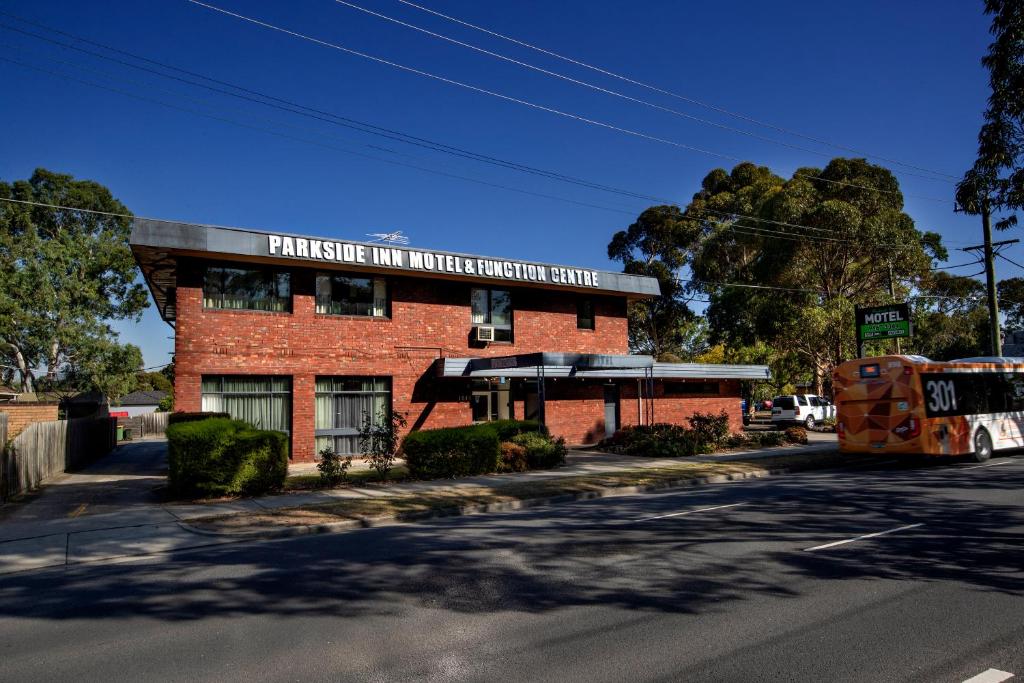 墨尔本Parkside Inn Motel的一条有公共汽车的街道上的红砖建筑