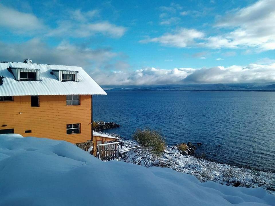 圣卡洛斯-德巴里洛切Berkana hostel Bariloche的水体旁的雪中房子
