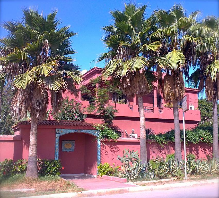 卡萨布兰卡达尔塔拉酒店的前面有棕榈树的粉红色建筑