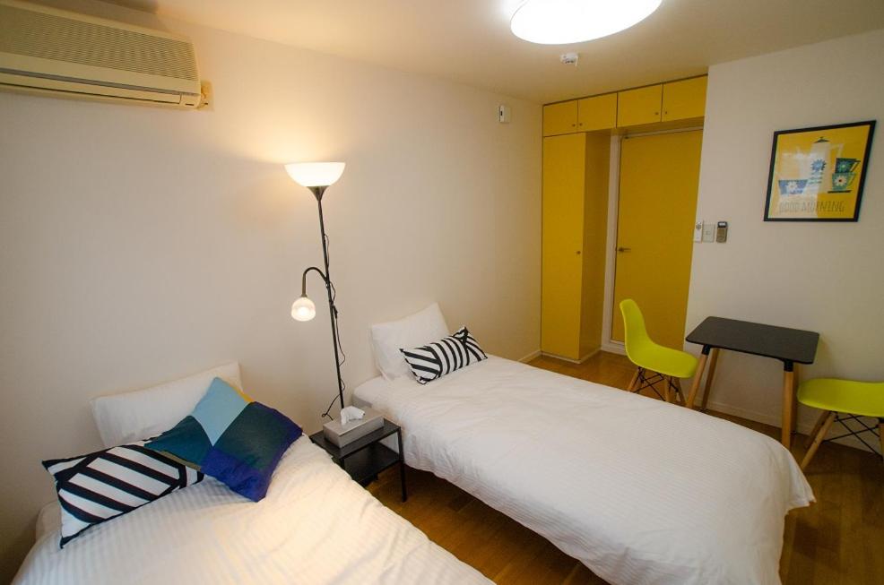 德岛Melody Heim 2C的客房设有两张床、一张桌子和一盏灯。