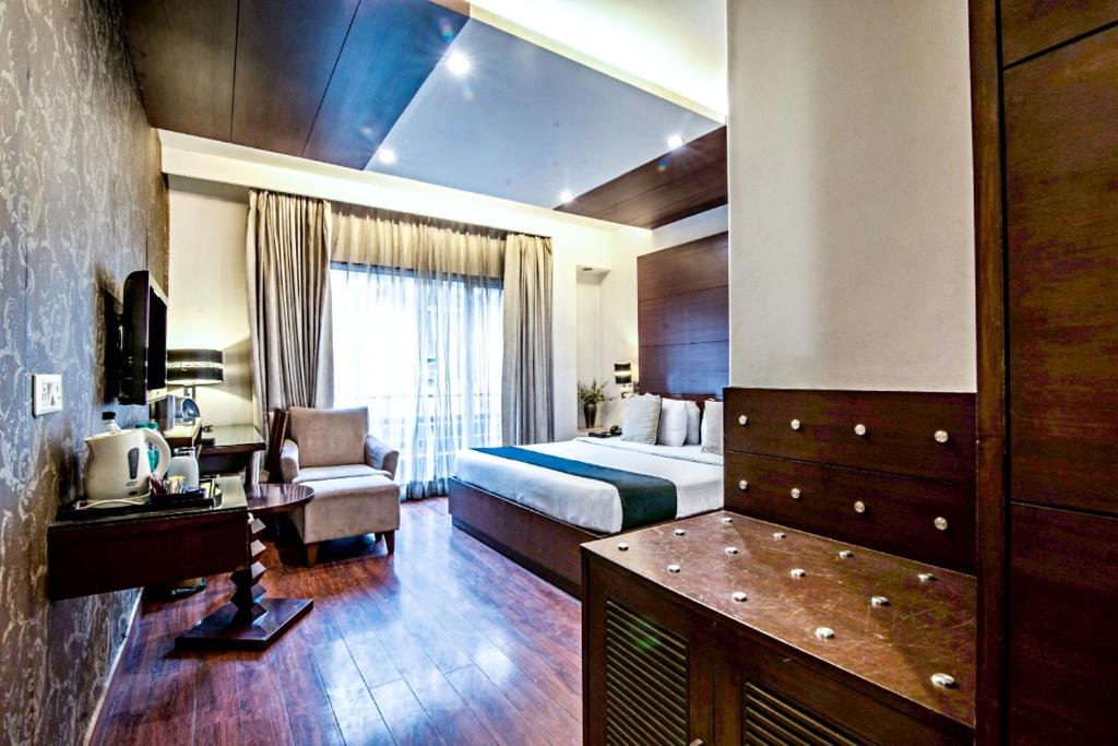新德里The Grand Vikalp By Saga Hotels的配有一张床和一把椅子的酒店客房