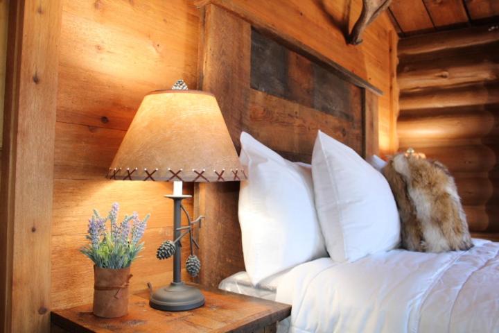 西黄石Elkhorn Cabins and Inn的一间卧室配有一张床和一张桌子上的台灯