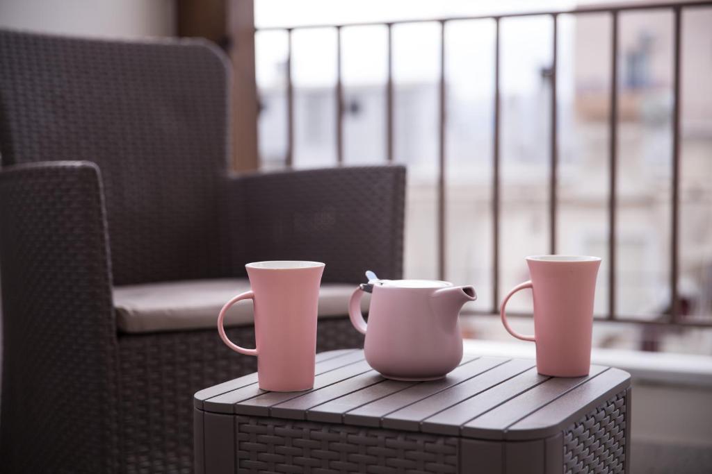 雅典Dream penthouse2的坐在椅子旁边的桌子上,两只粉红色的杯子
