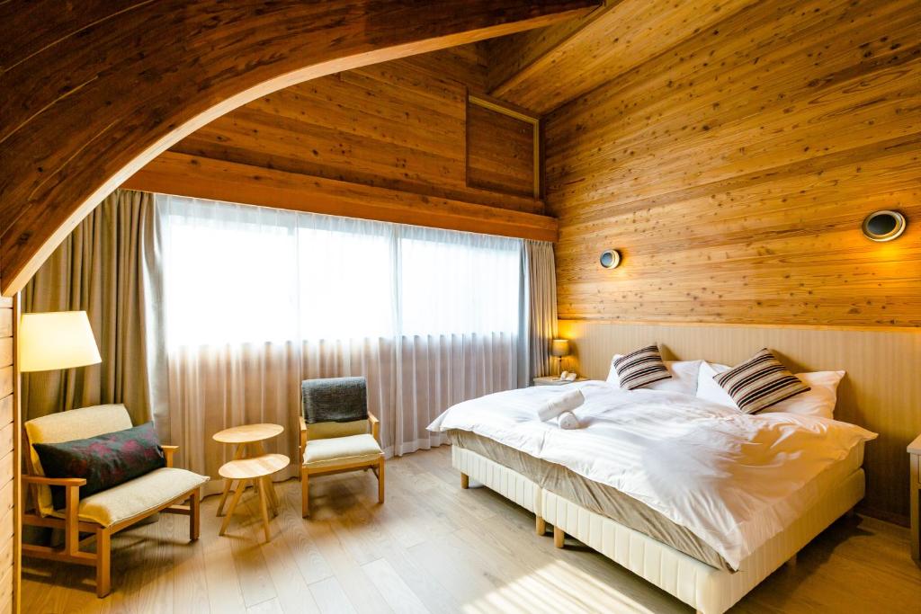 白马村Wadano Gateway Suites & Apartments的一间卧室设有一张床和木墙