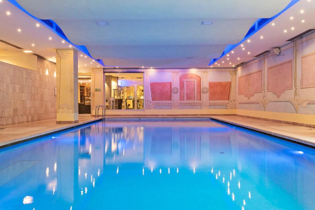 特雷维索玛吉尔康斯格里奥酒店的大楼内的一个蓝色海水游泳池