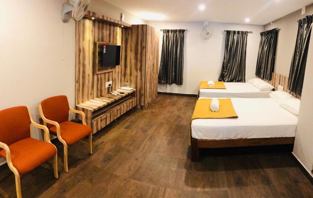 SomvārpetSharada Residency的酒店客房,配有两张床和两把椅子