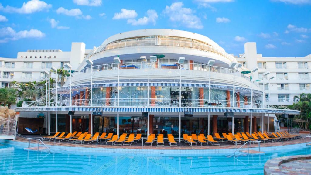 埃拉特Club Hotel Eilat - All Suites Hotel的一座带椅子和游泳池的大型建筑
