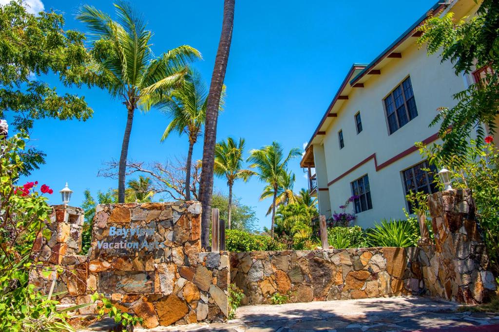 维尔京戈尔达岛Bayview Vacation Apartments的一座棕榈树和石墙的房子