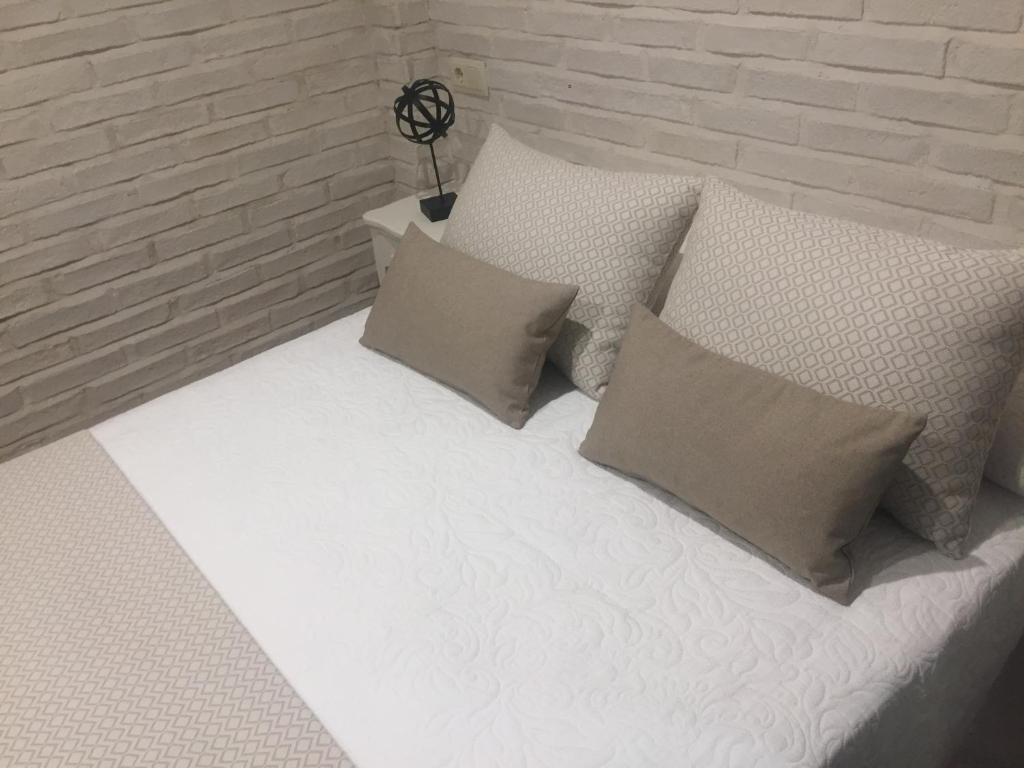 托莱多Ático del Rojas的一张带枕头的白色床和砖墙