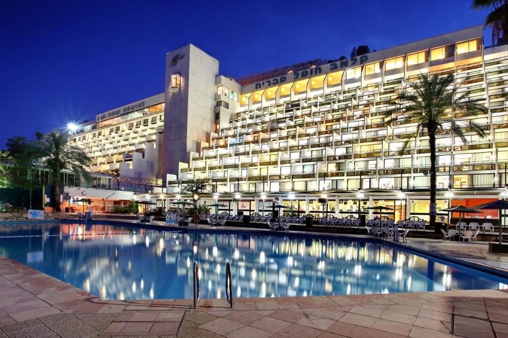 提比里亚Club Hotel Tiberias - Suites Hotel的一座大型建筑,晚上设有游泳池