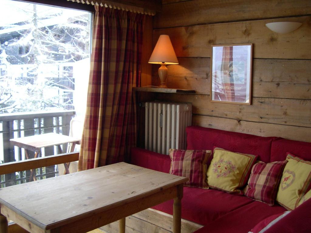 夏蒙尼-勃朗峰Studio Les Drus / Studio du Brévent的客厅配有红色的沙发和桌子