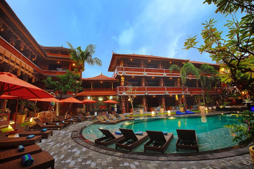 库塔库塔巴厘岛温纳别墅假日酒店的一座带游泳池和椅子的酒店和一座建筑