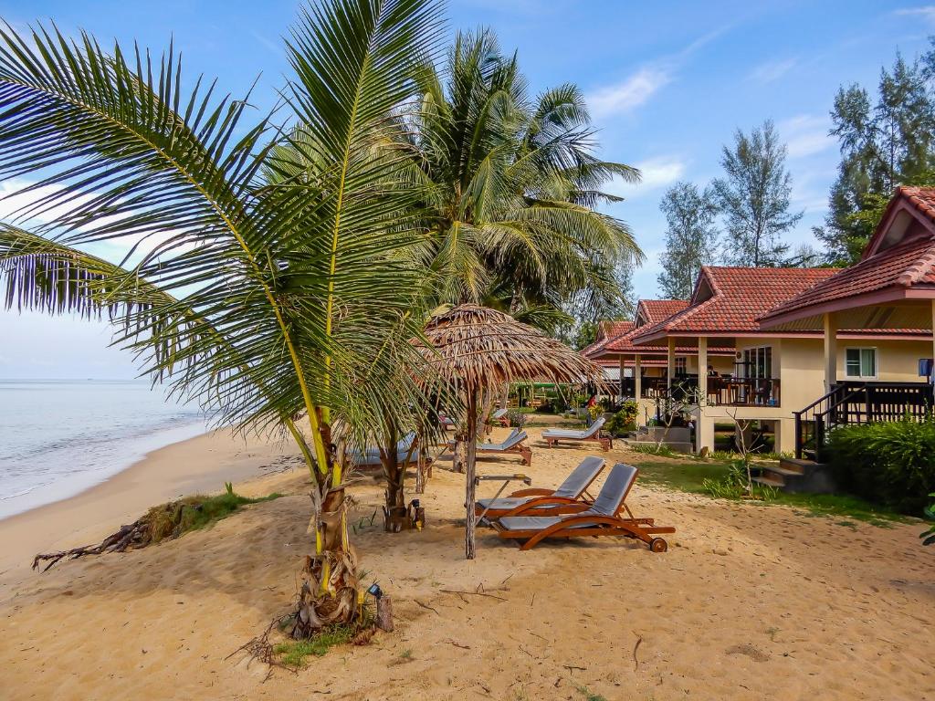 阁科考普拉尼海滩别墅酒店的海滩上,有椅子,棕榈树和房子