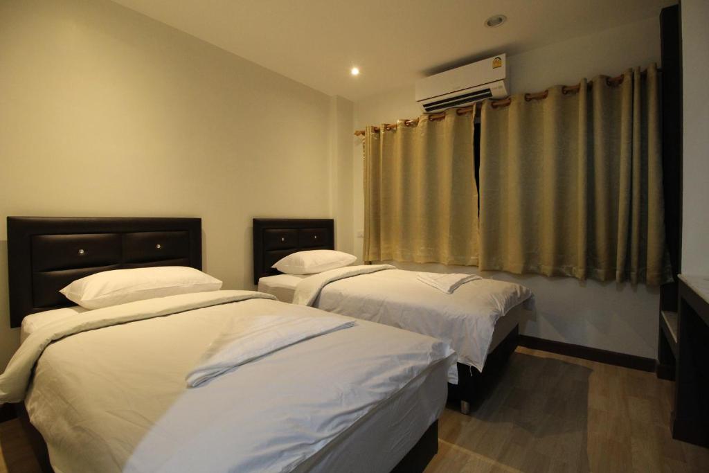 曼谷采瓦旅舍的一间卧室设有两张床和窗户。