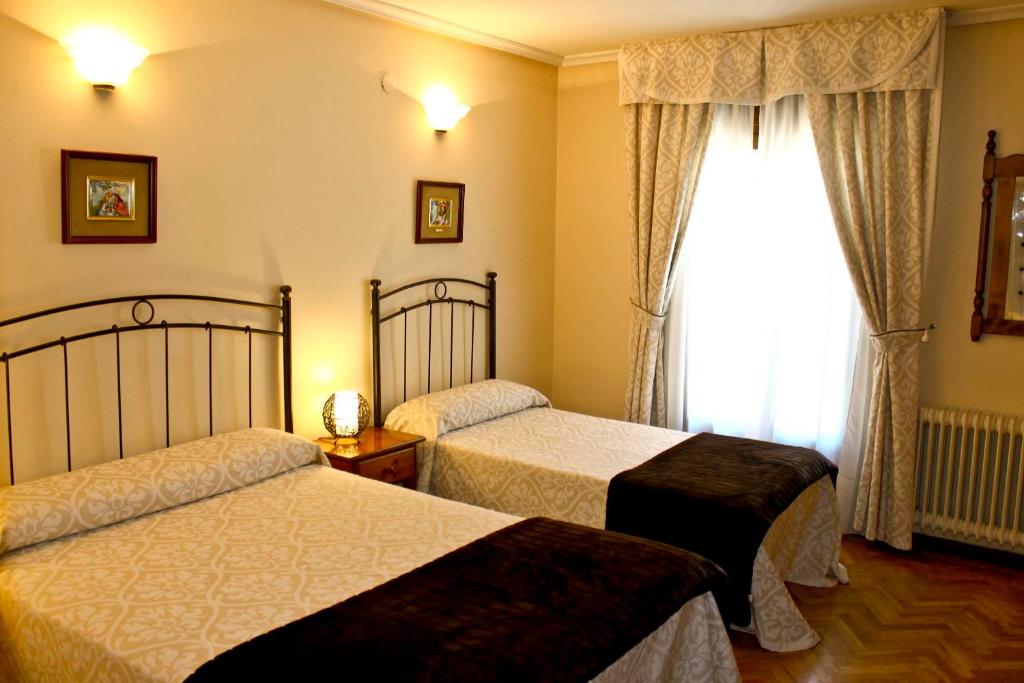 阿维拉阿尔坎塔拉旅舍的酒店客房设有两张床和窗户。