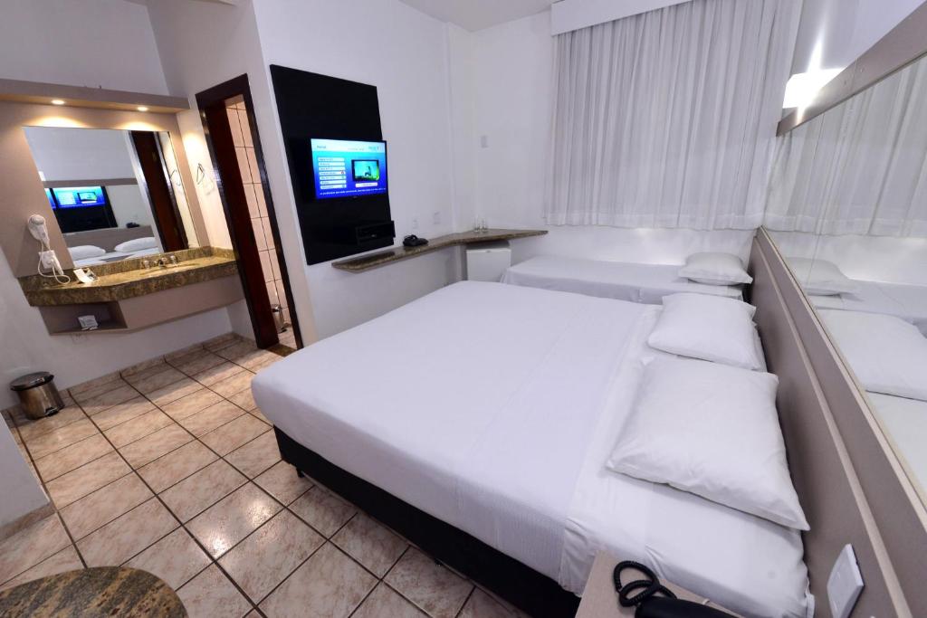 伊帕廷加Panorama Tower Hotel的一间带白色大床的卧室和一间浴室
