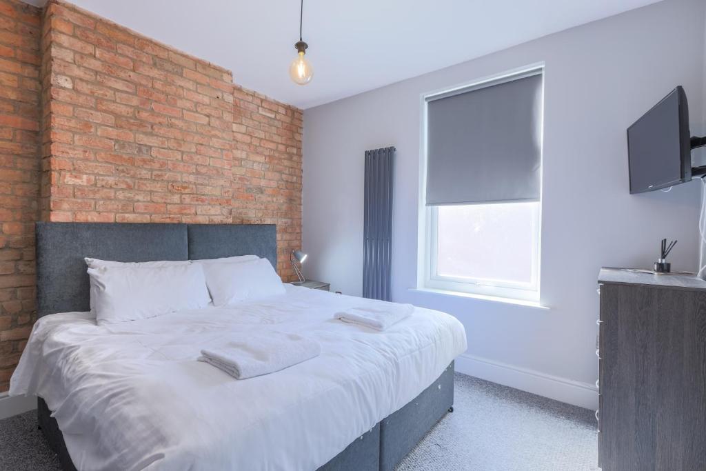 朗伊顿Salisbury Street Guesthouse的一间卧室设有一张带砖墙的大床
