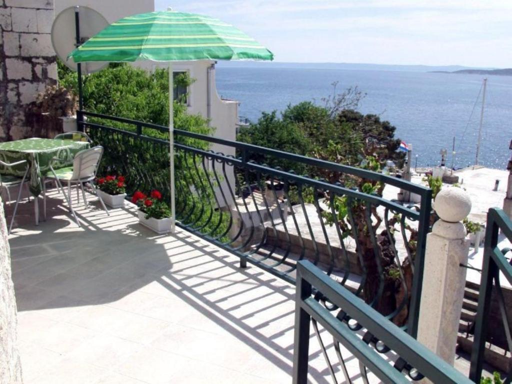 布雷拉villa NIKOLA的阳台配有桌子和雨伞。