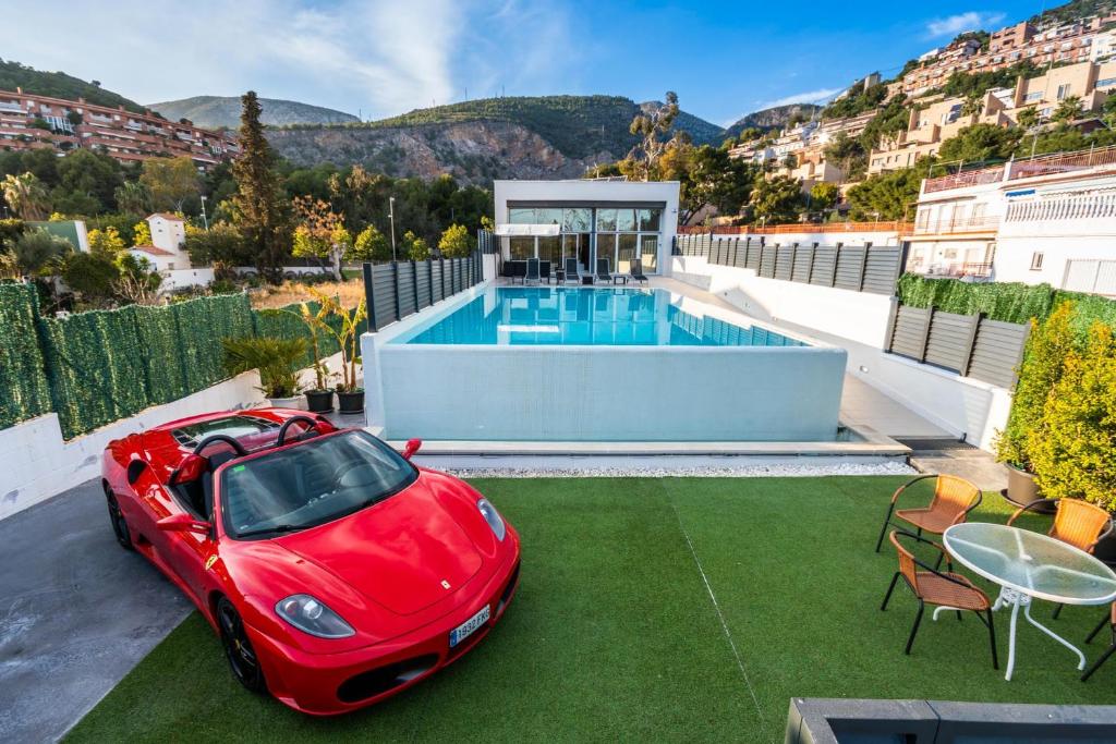 卡斯特尔德费尔斯Luxurious Villa Marly I to two minutes the beach的一辆红色的汽车停在一座带游泳池的房子的顶部