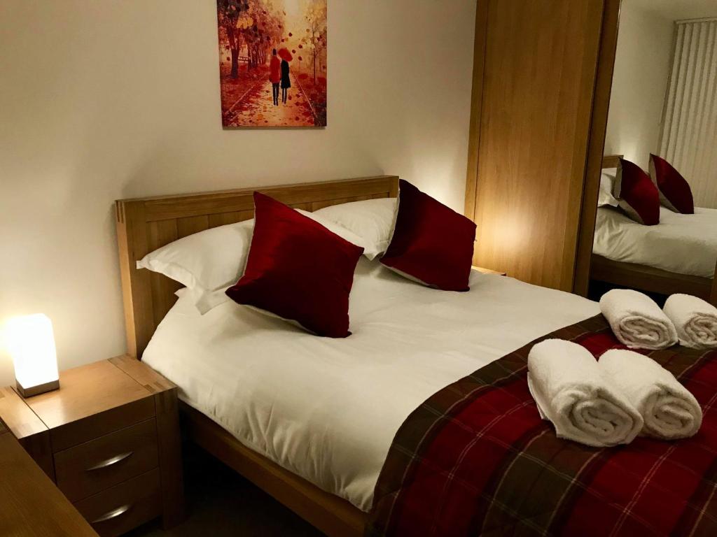 因弗内斯exploreNESS Apartment的一间卧室配有两张带红白色枕头的床