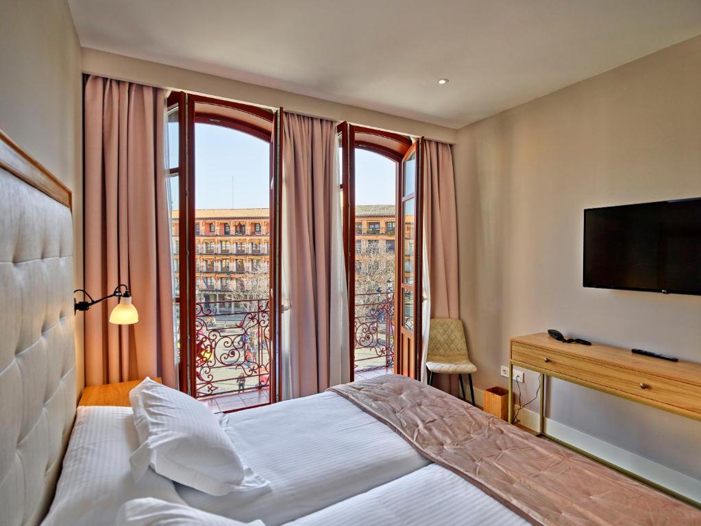 托莱多Hotel Boutique Adolfo的酒店客房设有一张床和一个大窗户