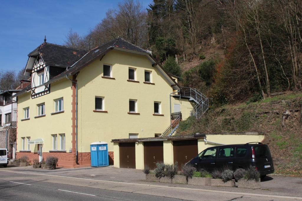 埃特林根Gästehaus Windheim (Ettlingen)的一座黄色的房子,前面有一辆汽车