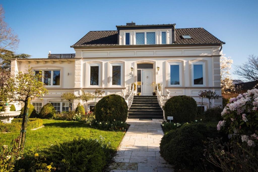 费马恩Villa Rosengarten的一座大型白色房子,在院子里设有楼梯