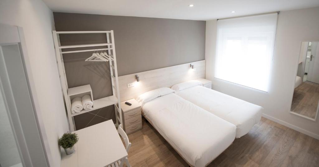 布尔戈斯卡拉乐斯幸福旅馆的一间小卧室,配有白色的床和书架