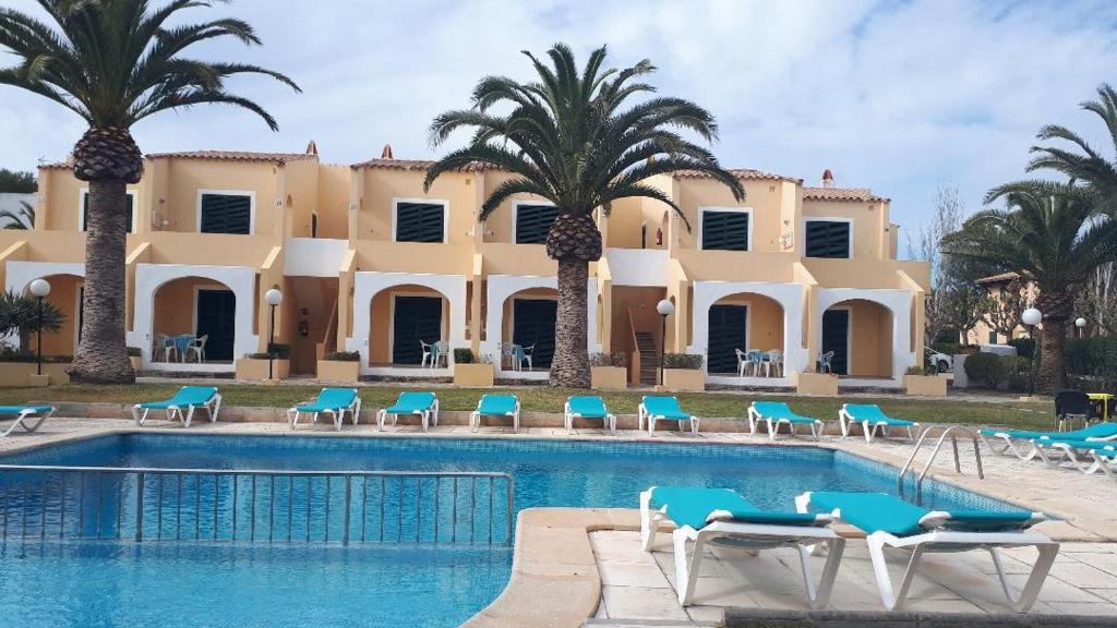 卡兰博希Apartamentos Costa Menorca的一个带游泳池和棕榈树的度假村