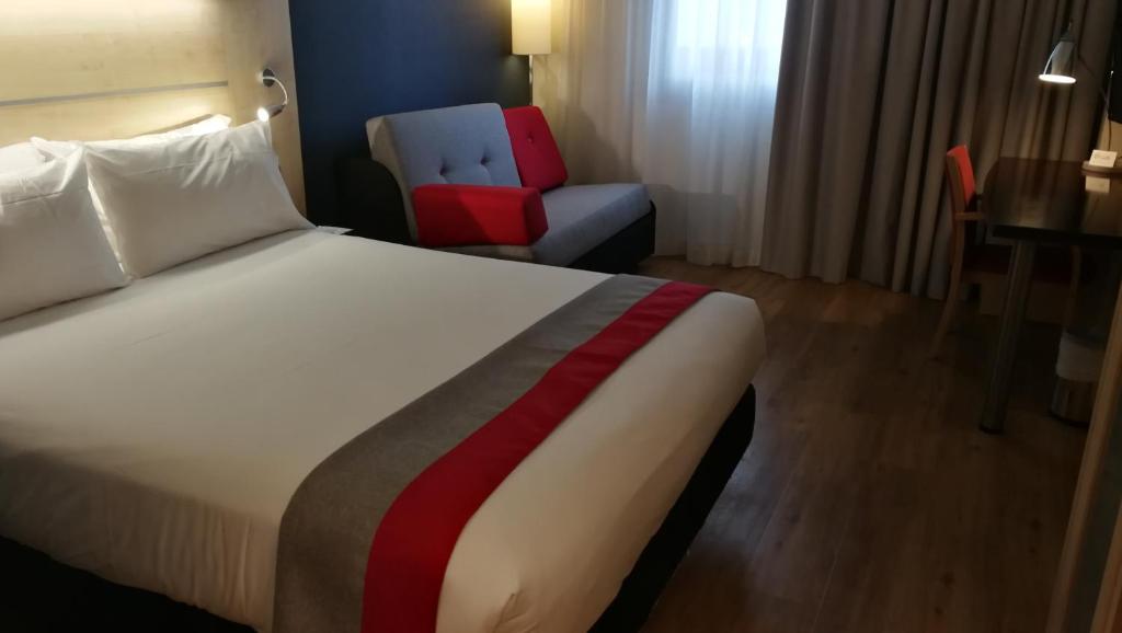 马拉加Holiday Inn Express Málaga Airport, an IHG Hotel的配有一张床和一把椅子的酒店客房