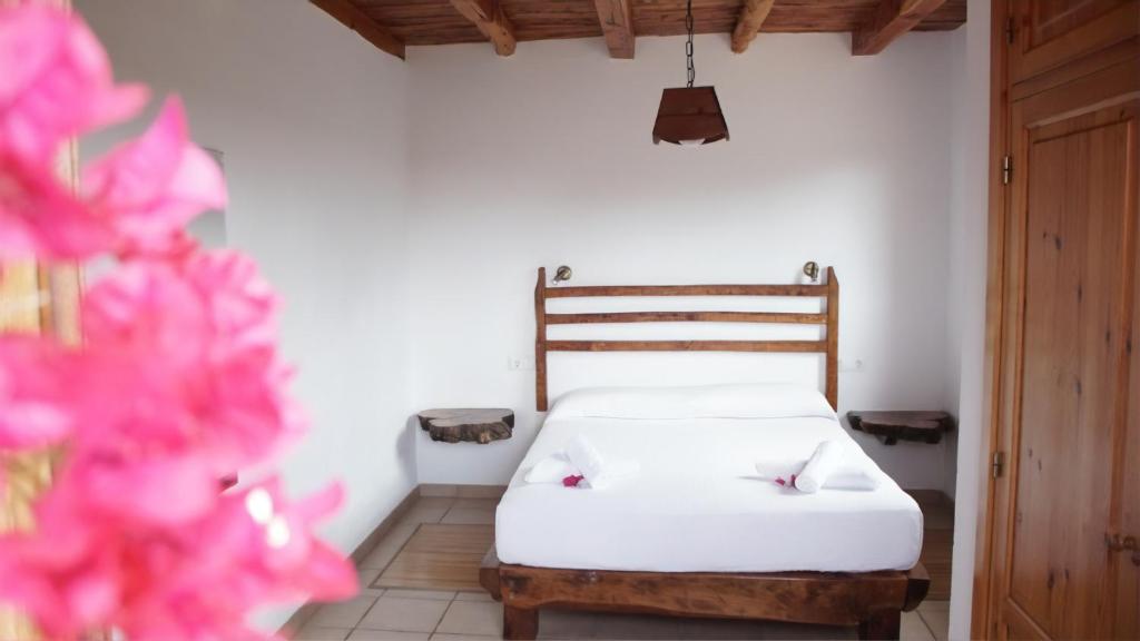 圣弗朗西斯科哈维尔Casa Rustick的一间卧室配有白色床单和粉红色鲜花。