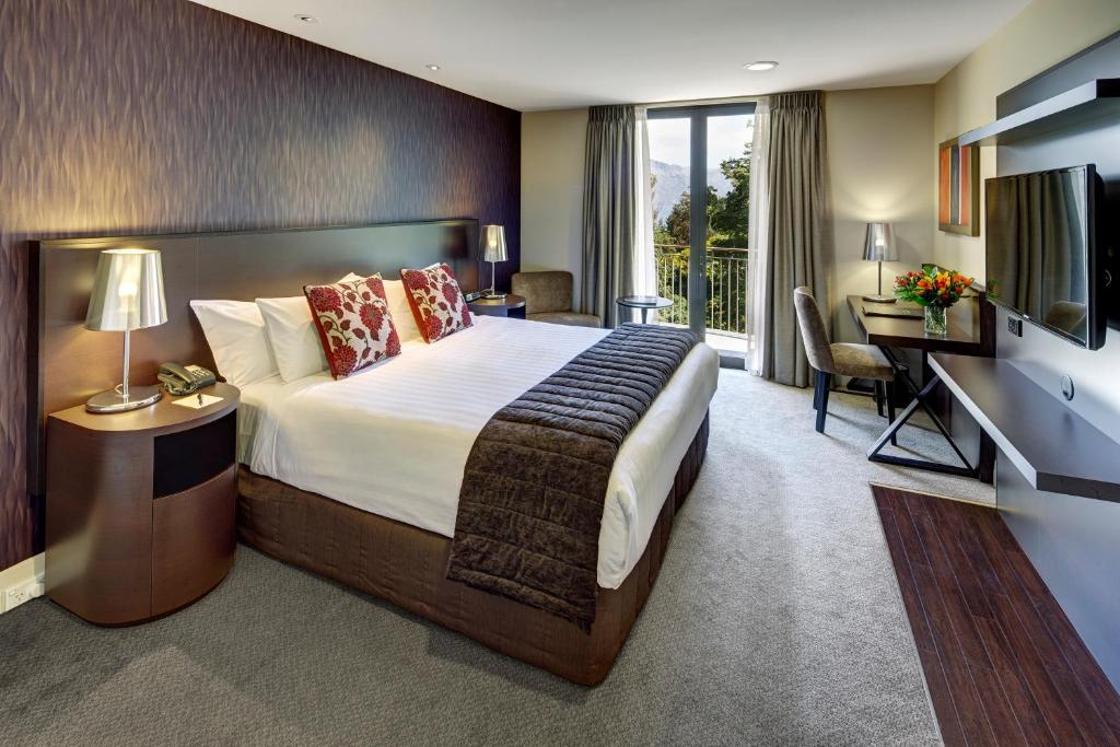 皇后镇Rendezvous Heritage Hotel Queenstown的配有一张大床和一张书桌的酒店房间