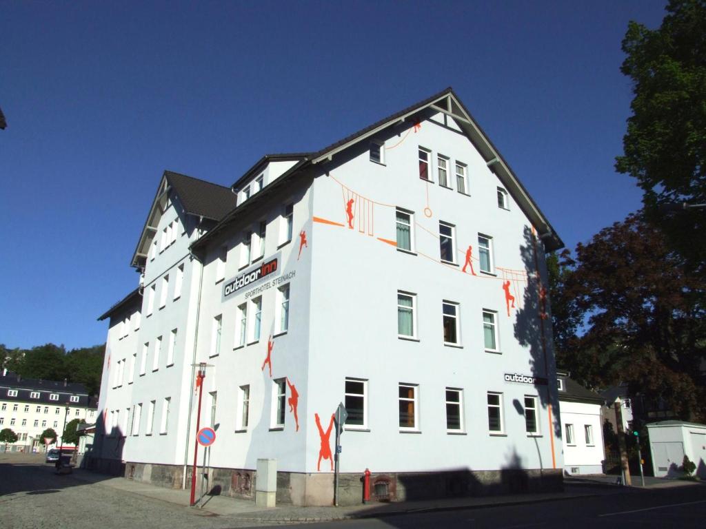 施泰纳赫史坦纳河户外健身酒店的一座白色的大建筑,上面有红旗