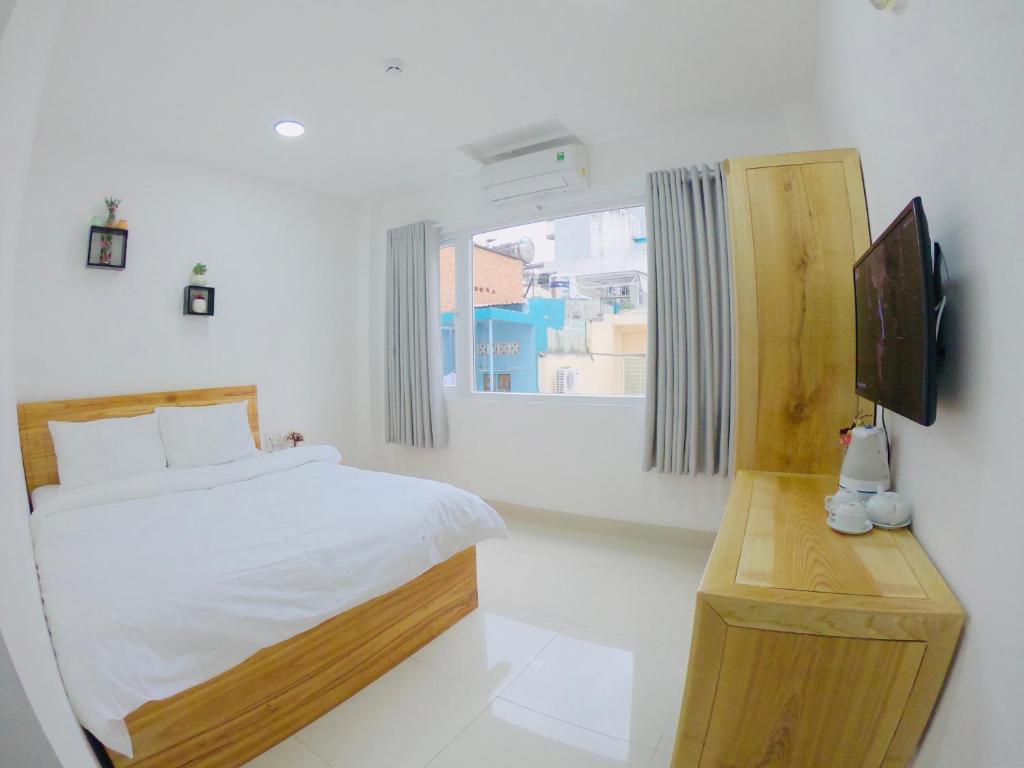 胡志明市Phan Anh Hotel - Bui Vien Walking Street的一间白色卧室,配有床和电视