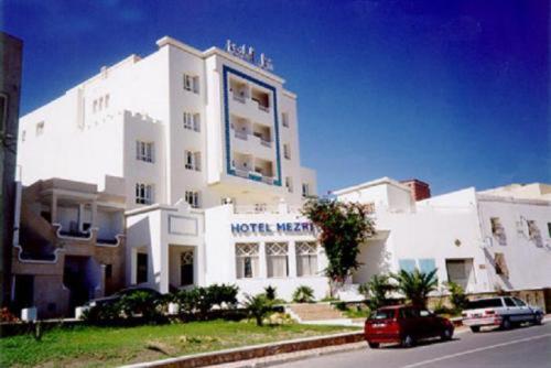 莫纳斯提尔梅兹里酒店的前面有一辆汽车停放的白色建筑