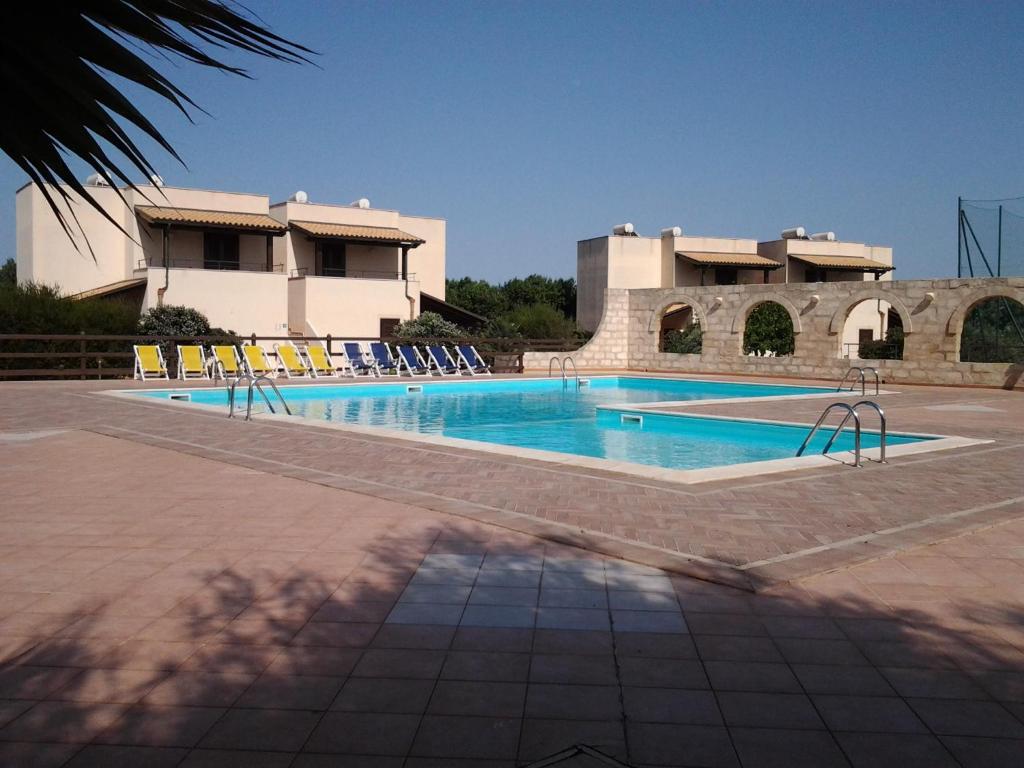 法维尼亚纳Residence Punta Longa的一座大楼前的游泳池,配有躺椅