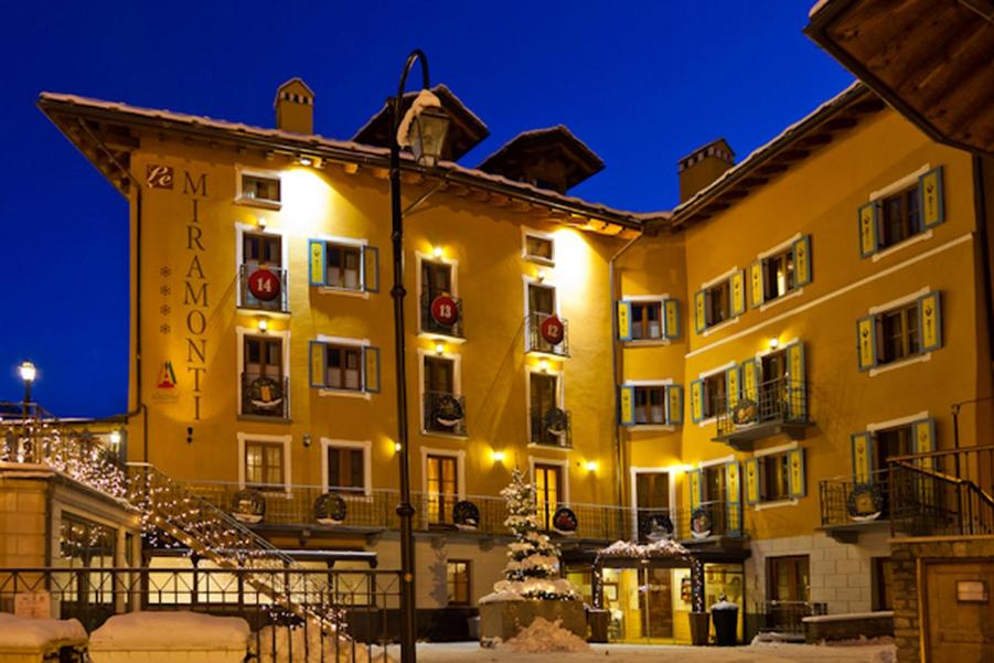 拉特乌伊莱Le Miramonti Hotel Restaurant & Wellness的一座黄色的大建筑,上面有圣诞灯