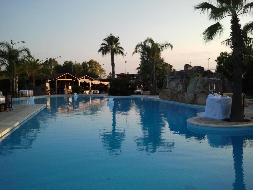 曼杜里亚Villaggio Turistico Malibuù的度假村内一座种有棕榈树的大型游泳池