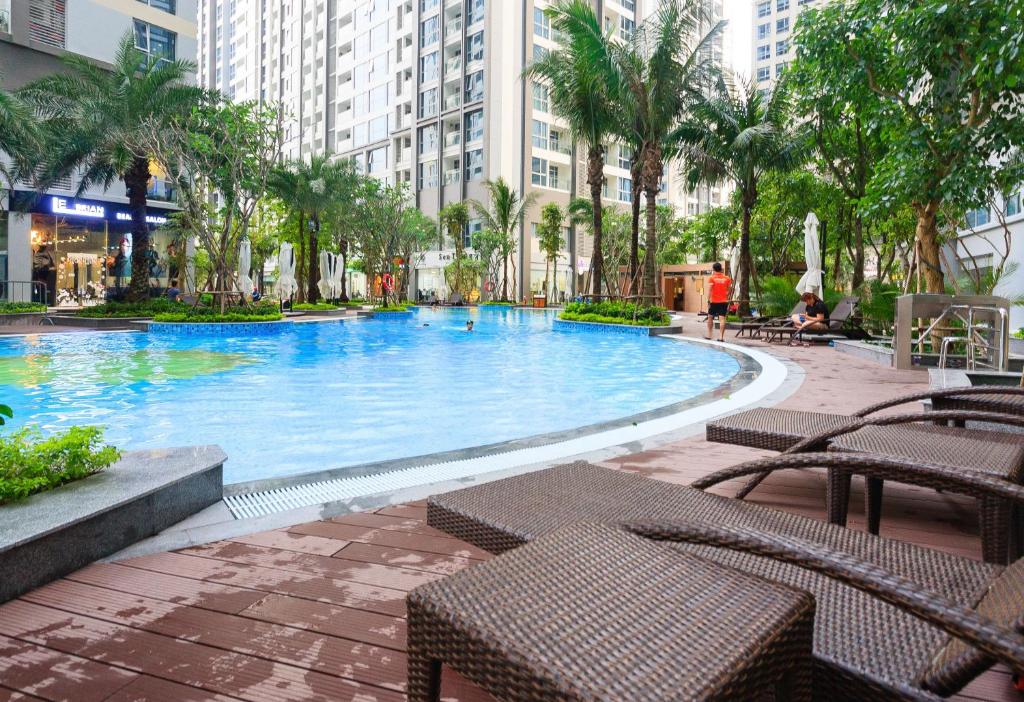 胡志明市Vinhomes Premium Apartment的一座带长椅和棕榈树的大型游泳池