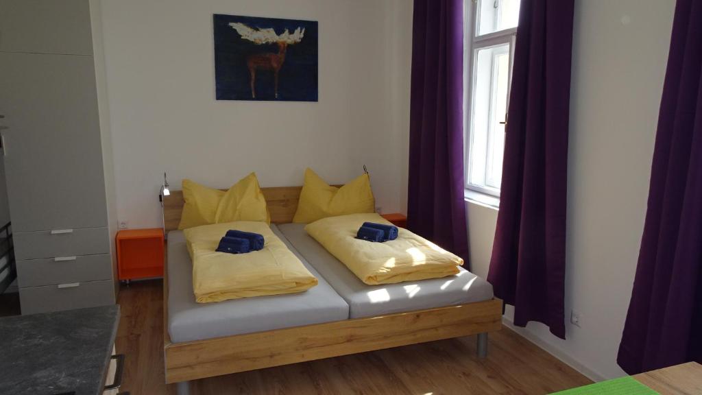 维也纳Luna Apartments的窗户间里一张带黄色枕头的床